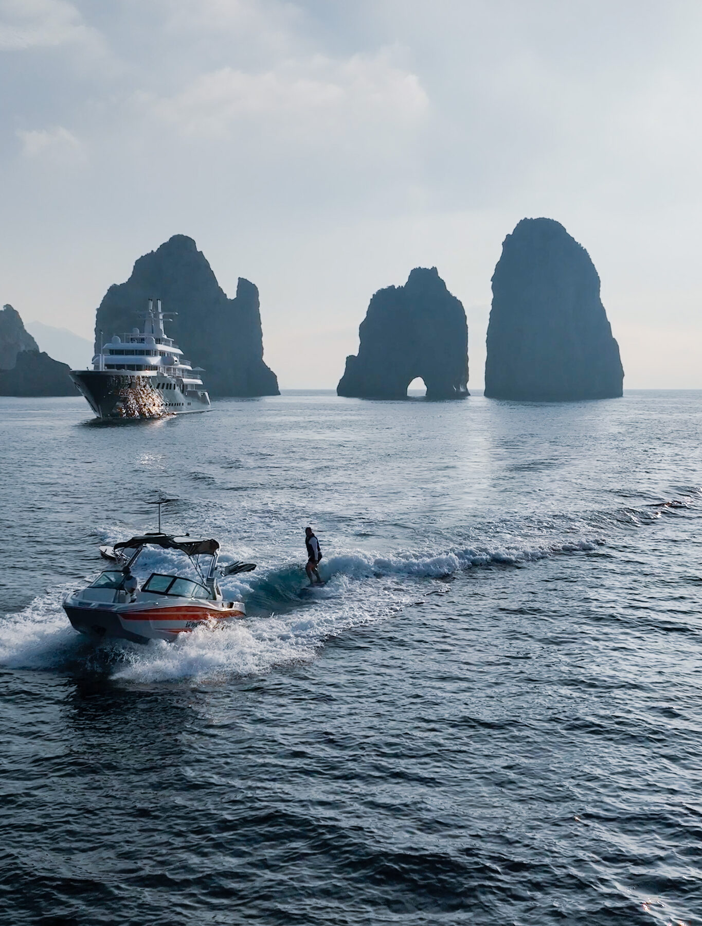 Wakesurfing past the Faraglioni at Capri with a superyacht behind