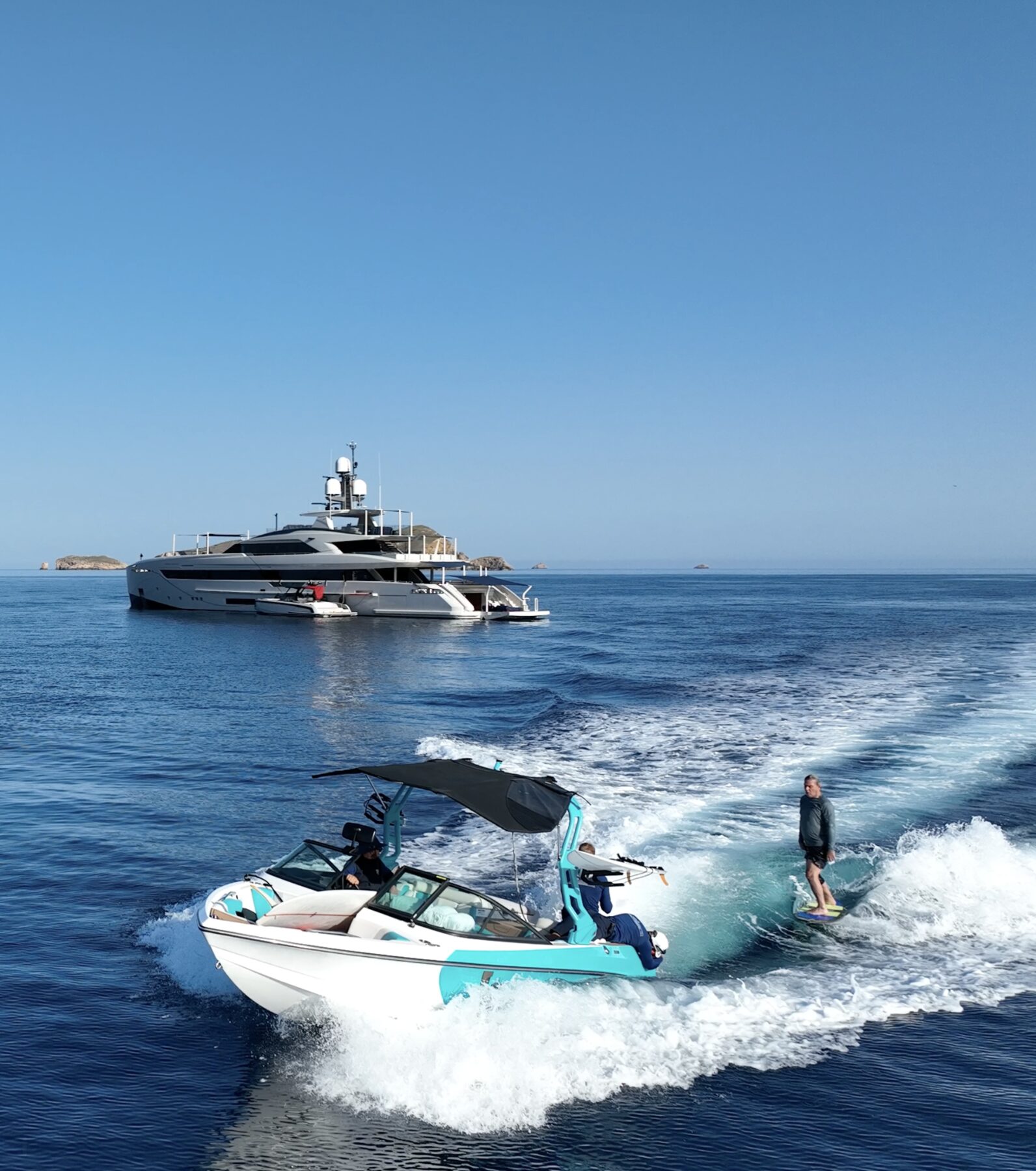 Wakesurfing behind a wake tender with a superyacht at anchor